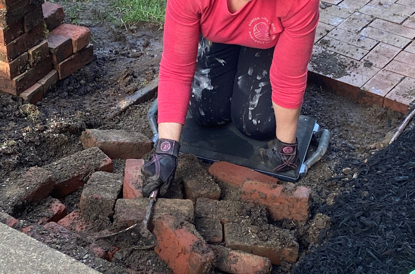 Female gardener creating brick walkway